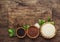 Black, white and red quinoa in spoons, raw quinoa groats assorted, wooden rustic kitchen table, top view