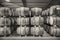 Black and white rows of stacks of traditional full whisky barrels, set down to mature, in a large warehouse