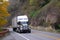 Black and white Semi truck reefer trailer on autumn highway