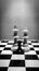 Black and white shot of chess pieces of a white king and queen and a black pawn standing in front of them on a chessboard