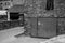 Black and white shot of a small locked metallic door on the wall of a n old house