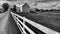 A black and white shot of a traditional Amish barn and a white picket fence in the middle of Ohio, USA