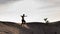 A black and white silhouette view of a young man running freely at the center of desert with sunset as background at Klebang Beach