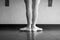 Black and white version of back view of ballet dancer ballerina at the barre in dance class standing in first position