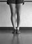 Black and white version of dancer`s legs in jazz first position at the barre