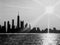 Black and White view of Chicago skyline seen from Lake Michigan, with sunset and sunbeams extending over cityscape during summer