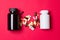 Black and white vitamin container and pills on red colored paper background