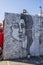 A black and white wall mural with a woman’s face in Little Five Points surrounded by parked cars with a gorgeous clear blue sky