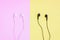 Black and White wired earphones on pink and yellow background