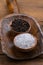 Black whole peppercorns and blue crystal salt in wooden bowls on an old flour shovel
