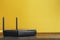 Black Wi-Fi router on a yellow background with free space