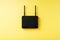 Black Wi-Fi router on a yellow background with free space