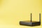 Black Wi-Fi router on a yellow background with free space