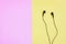 Black wired earphones on pink and yellow background