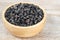 Black wolfberries or black goji berries, in a wooden bowl