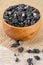 Black wolfberries or black goji berries, in a wooden bowl