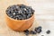 Black wolfberries or black goji berries, in a wooden bowl on table