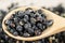 Black wolfberries or black goji berries, in a wooden spoon on table
