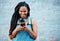 Black woman with 5g smartphone for social media typing, digital chat app or check location on blue wall background space