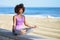 Black woman, afro hairstyle, doing yoga in the beach