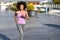 Black woman, afro hairstyle, running outdoors in urban road.