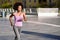 Black woman, afro hairstyle, running outdoors in urban road.