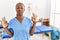 Black woman with braids working at pain recovery clinic relaxed and smiling with eyes closed doing meditation gesture with fingers