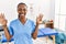 Black woman with braids working at pain recovery clinic showing and pointing up with fingers number nine while smiling confident