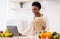 Black Woman Cooks Using Laptop Searching Recipes Online In Kitchen