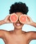 Black woman, face and hands with grapefruit for skincare nutrition, beauty or vitamin C against a blue studio background