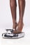 Black woman, feet and scale to measure weight, diet and weightloss against a white studio back with mockup. Foot, health