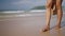 Black woman feet walking on sandy ocean beach at exotic island along sea water waves. Dark skin female legs go by surf