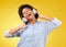 Black woman, headphones and freedom, listening to music and happiness with dance on yellow studio background. Happy
