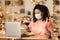 Black woman in mask having dinner waving to laptop