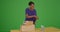 A black woman receiving package delivery and brining it inside on green screen