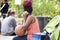 Black woman with red braids sits at the Gathering Place holding a basketball and talking on a pink phone