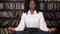 Black woman in white blouse sits in yoga pose lotus on table