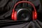 Black wooden audio speaker and red headphones in a natural silk interior. The concept of audio broadcasting and audio streaming.