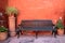 Black wooden bench in front of orange color rough wall with many terracotta planters, Santa Catalina Monastery in Arequipa