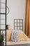 Black wooden grille next to the bed with orange bedding in the bedroom with white walls