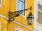 Black wrought iron wall lantern on a yellow wall.