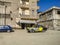 A black and yellow dilapidated Lada taxi driving through the beaten road in Alexandria