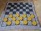 Black and yellow plastic checkers on fabric checkerboard