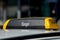 Black and yellow Yango taxi sign on a car roof against blurry background