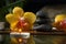 Black zen stones, candles and yellow orchids on a wooden plank on the surface of the water. SPA, relaxation, meditation