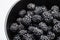 Blackberries in a black bowl, ripe fresh berries macro photo