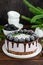 Blackberry cream mousse cake no baked cheesecake with chocolate glaze and frozen blackberry on top on a white plate