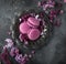 Blackberry macarons on vintage plate and lilac flowers over grey