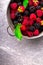 Blackberry and raspberry in a metal bowl on grey wooden background. Top view.