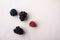 Blackberry and raspberry scattered heap four berries on white wooden background copy space, isolated, top view